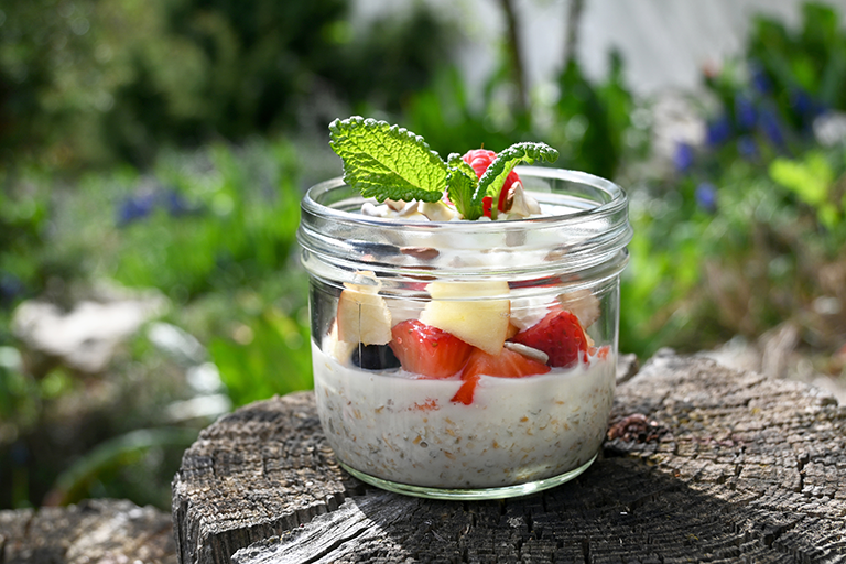 Frischkornbrei mit Apfel- und Erdbeerstücken in einem verzierten Glas