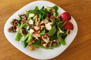 Winter-Salat mit Feldsalat, Äpfeln und Walnüssen in einem weißen Teller